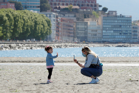 Một phụ nữ và một đứa trẻ xuất hiện trên bãi biển ở Naples, Ý hôm 4-5 khi nước Ý bắt đầu dần kết thúc tình trạng phong tỏa theo giai đoạn - Ảnh: REUTERS Một phụ nữ và một đứa trẻ xuất hiện trên bãi biển ở Naples, Ý hôm 4-5 khi nước Ý bắt đầu dần kết thúc tình trạng phong tỏa theo giai đoạn - Ảnh: REUTERS