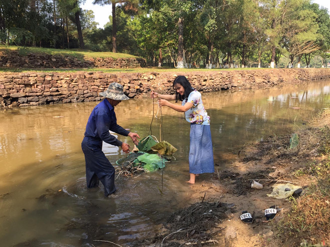 Chị Diệu Huyền đích thân xuống hồ sen để tìm hiểu cách trồng loại sen trắng