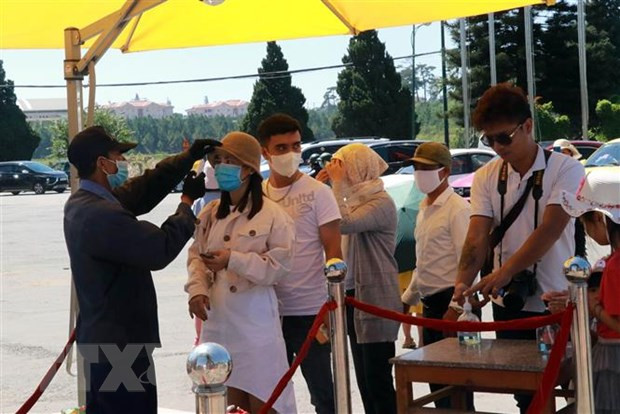 Du khách được đo thân nhiệt, khử trùng trước khi vào tham quan Vườn hoa thành phố Đà Lạt. (Ảnh: Chu Quốc Hùng/TTXVN)