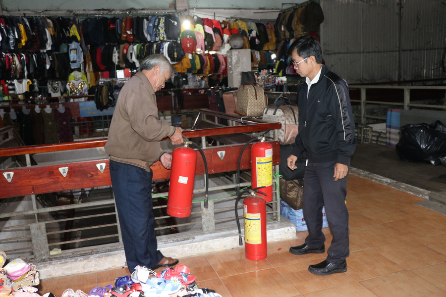 Thành viên Ban quản lý chợ An Khê kiểm tra bình cứu hỏa tại khu vực buôn bán giày dép, quần áo. Ảnh: Ngọc Minh