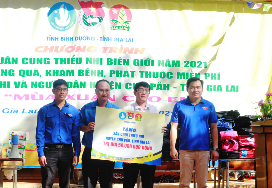 Ảnh 2: Anh Trần Bảo Lâm (bìa phải)-Phó Bí thư Tỉnh Đoàn Bình Dương trao bảng tượng trưng công trình vui chơi trị giá 50 triệu đồng cho Trường THCS xã Ia Kreng.