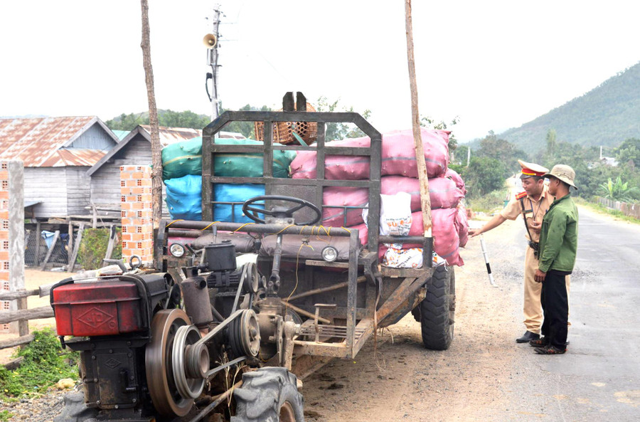 Cảnh sát Giao thông Công an thị xã Ayun Pa nhắc nhở người dân không được chở người trên thùng xe công nông và kiểm tra đèn chiếu sáng. Ảnh: Hữu Trường