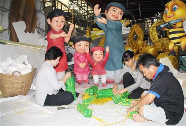 Các công nhân làm mô hình bánh trưng, bánh tét trang trí Đường hoa Nguyễn Huệ. (Ảnh: Mỹ Phương/TTXVN)