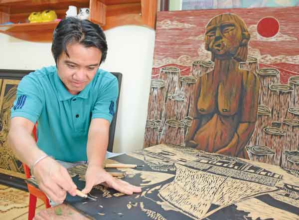 Họa sĩ Nguyễn Văn Chung miệt mài sáng tạo một bức tranh sơn khắc. Ảnh: Phương Duyên