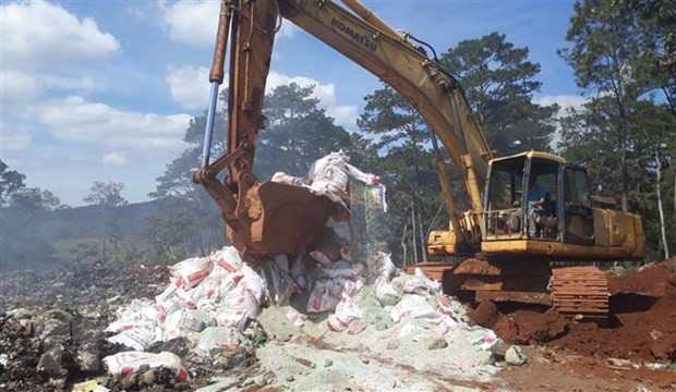 Lực lượng chức năng huyện Bảo Lâm dùng xe cơ giới phá hủy các bao phân bón trước khi chôn lấp để tiêu hủy hoàn toàn. (Ảnh: TTXVN phát)