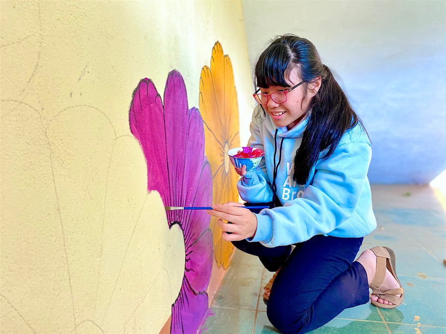 Tâm tỉ mẩn hoàn thiện bức tranh hoa lá mùa xuân trên bức tường lớp học. Ảnh: Mộc Trà