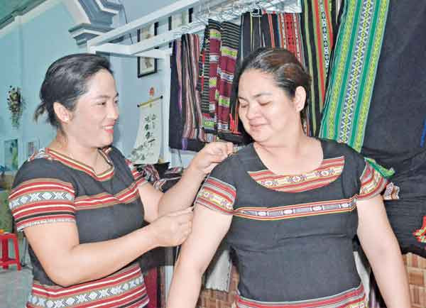 Để may được những bộ đồ đẹp, chị H’Tuyết (bìa trái) tỉ mỉ từ việc lấy số đo của khách hàng. Ảnh: Phương Linh