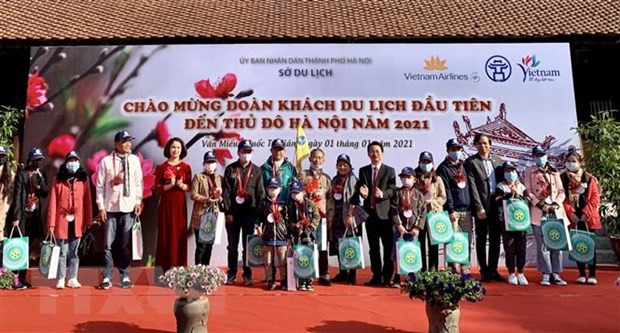 Lãnh đạo Sở Du lịch Hà Nội tặng quà cho đoàn khách đầu tiên năm 2021. (Ảnh: Đinh Thuận/TTXVN)