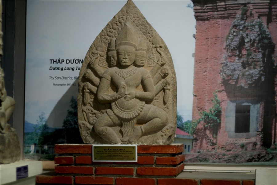 Thần không mặc áo, để lộ ra một cơ thể lực lưỡng, cường tráng. Thần đội mũ hình chóp, cổ và tay đeo trang sức, mặc một chiếc sampot được giữ ngang bụng bằng một dây thắt rộng bản trang trí các hình cánh sen, uốn lượn mềm mại, có vạt dài rủ xuống. Ảnh: N.T