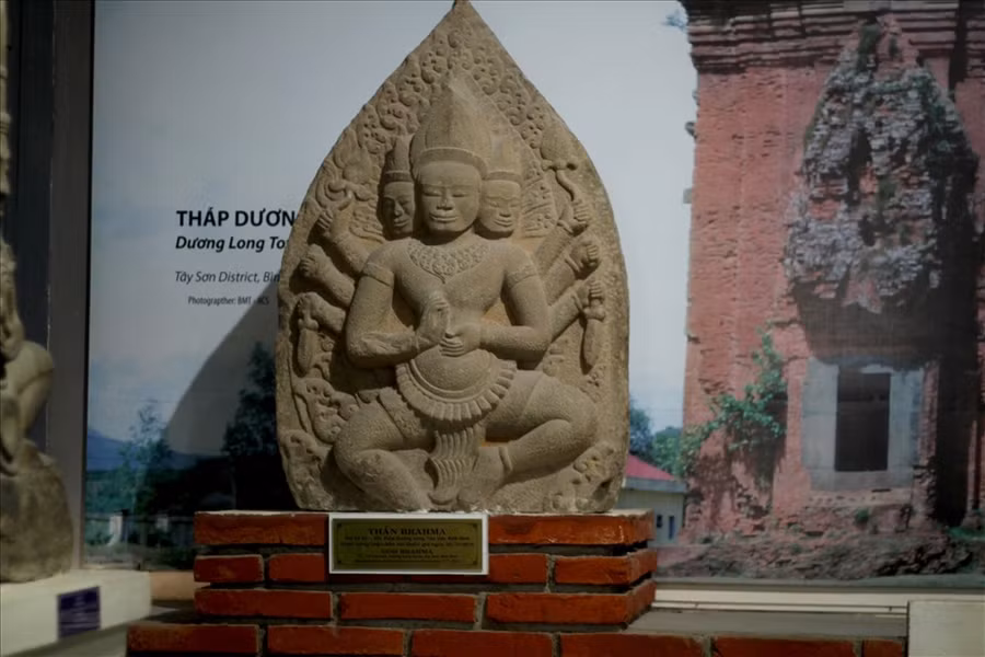 Thần không mặc áo, để lộ ra một cơ thể lực lưỡng, cường tráng. Thần đội mũ hình chóp, cổ và tay đeo trang sức, mặc một chiếc sampot được giữ ngang bụng bằng một dây thắt rộng bản trang trí các hình cánh sen, uốn lượn mềm mại, có vạt dài rủ xuống. Ảnh: N.T