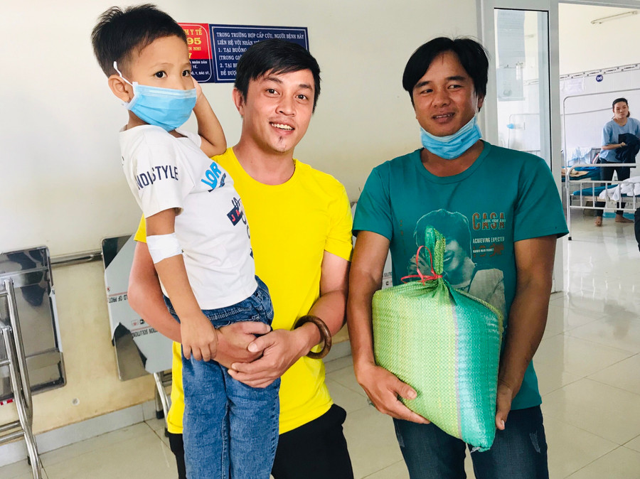 Anh Trần Vũ (ở giữa)-Chủ nhiệm CLB Máu nóng Gia Lai trao gạo hỗ trợ cho gia đình bệnh nhi Bùi Văn Bình bị bệnh Thalassemia. Ảnh: Phan Lài