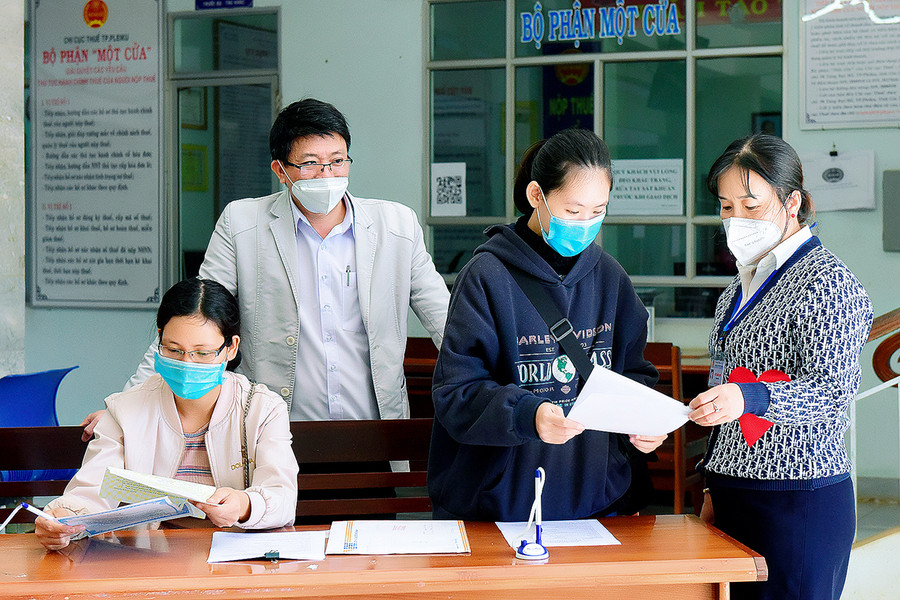  Cán bộ Chi cục Thuế TP. Pleiku hướng dẫn các hộ kinh doanh đăng ký nộp thuế. Ảnh: Đức Thụy