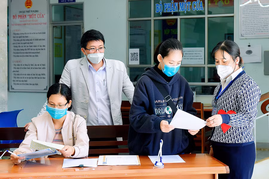  Cán bộ Chi cục Thuế TP. Pleiku hướng dẫn các hộ kinh doanh đăng ký nộp thuế. Ảnh: Đức Thụy