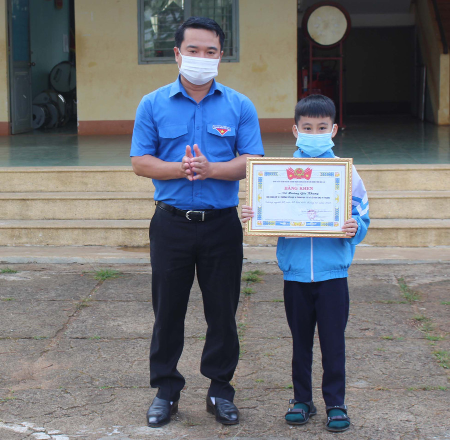 Anh Đỗ Duy Nam (bìa trái)-Phó Bí thư Tỉnh Đoàn, Chủ tịch Hội đồng Đội tỉnh tặng bằng khen gương người tốt-việc tốt cho em Võ Hoàng Gia Khang. Ảnh: Phan Lài