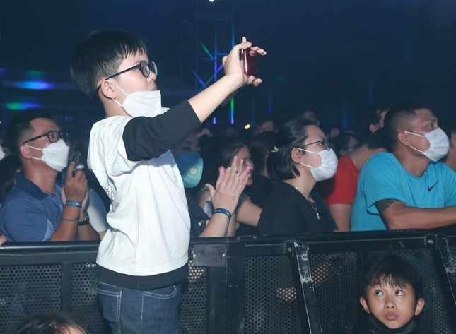 Một khán giả nhỏ tuổi ghi lại khoảnh khắc biểu diễn của các nghệ sĩ trên sâu khấu.