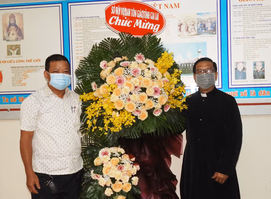 Trưởng Ban Tôn giáo tỉnh Hồ Hải Tần (trái) tặng lẵng hoa chúc mừng Linh mục trưởng Giáo hạt Pleiku Đinh Quang Vinh. Ảnh: Thanh Nhật 