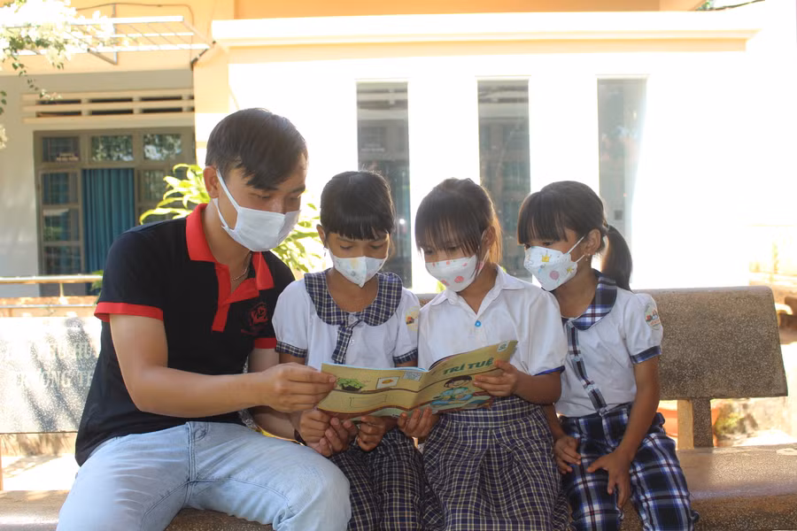 Anh Lê Tuấn Thành (bìa trái)-thành viên Câu lạc bộ Vòng tay yêu thương hướng dẫn các em học sinh Trường Tiểu học Lê Quý Đôn (xã Ia Krai, huyện Ia Grai) đọc sách. Ảnh: Phan Lài