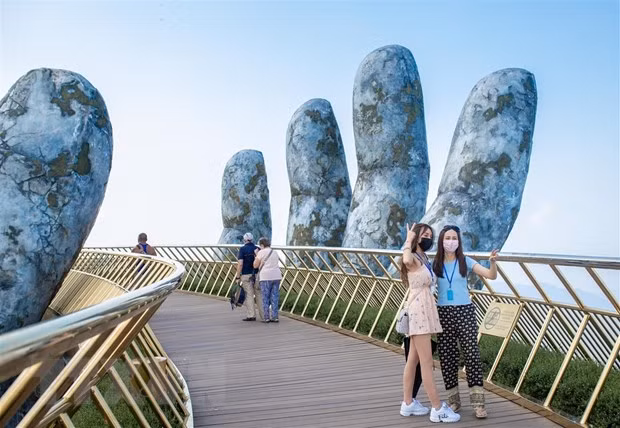 Du khách tham quan chụp ảnh tại cầu Vàng khu du lịch Sun World Ba Na Hills. Ảnh: TTXVN phát