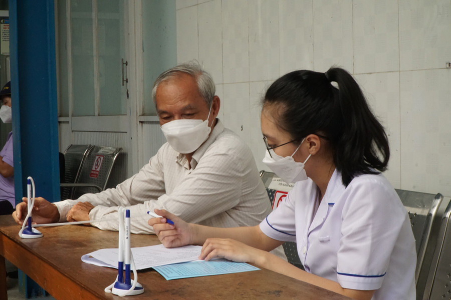 Nhân viên y tế giúp bệnh nhân điền thông tin, các triệu chứng hậu Covid-19 vào bảng đánh giá mức độ trước khi tư vấn. Ảnh: Khánh Trần