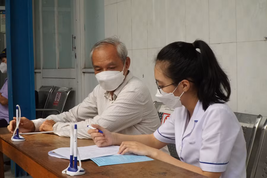 Nhân viên y tế giúp bệnh nhân điền thông tin, các triệu chứng hậu Covid-19 vào bảng đánh giá mức độ trước khi tư vấn. Ảnh: Khánh Trần