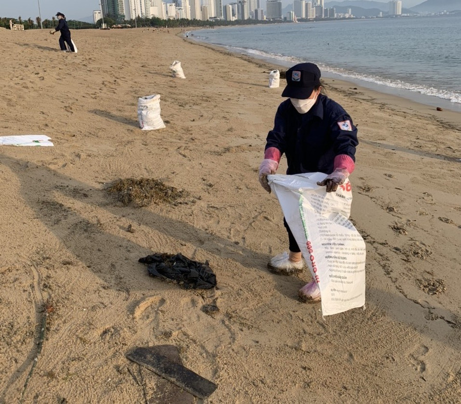 Nhân viên môi trường vớt dầu đen dạt vào bờ biển Nha Trang.