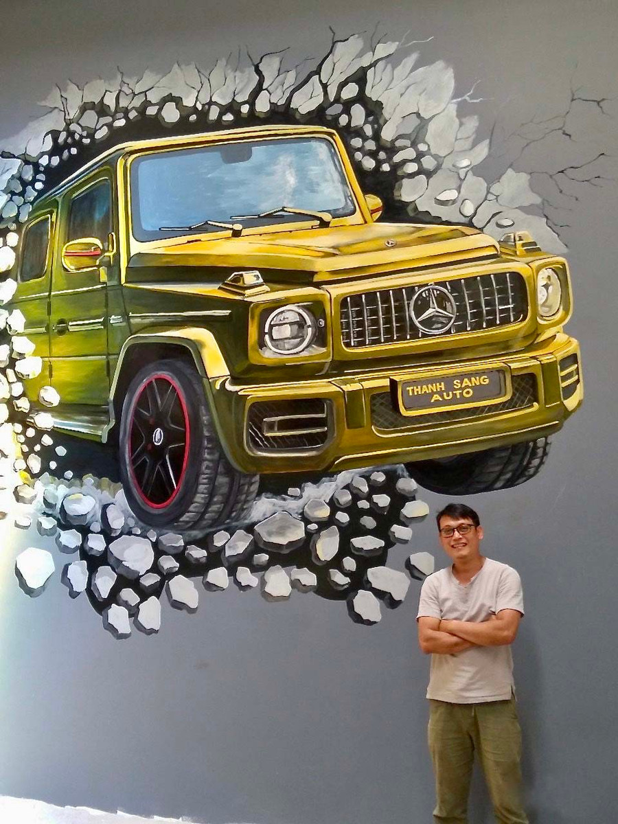 Họa sĩ Đinh Việt Thanh bên một tác phẩm tranh tường. Ảnh: Phương Duyên