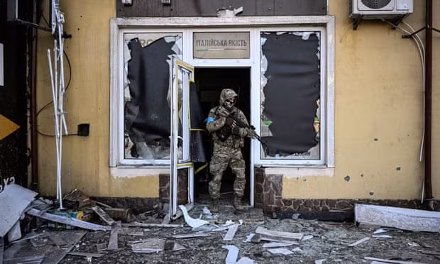 Một binh sĩ Ukraine rời khỏi một tòa nhà bị hư hại do pháo kích ở Kiev vào ngày 12/3. Ảnh: Aris Messinis/Getty Images