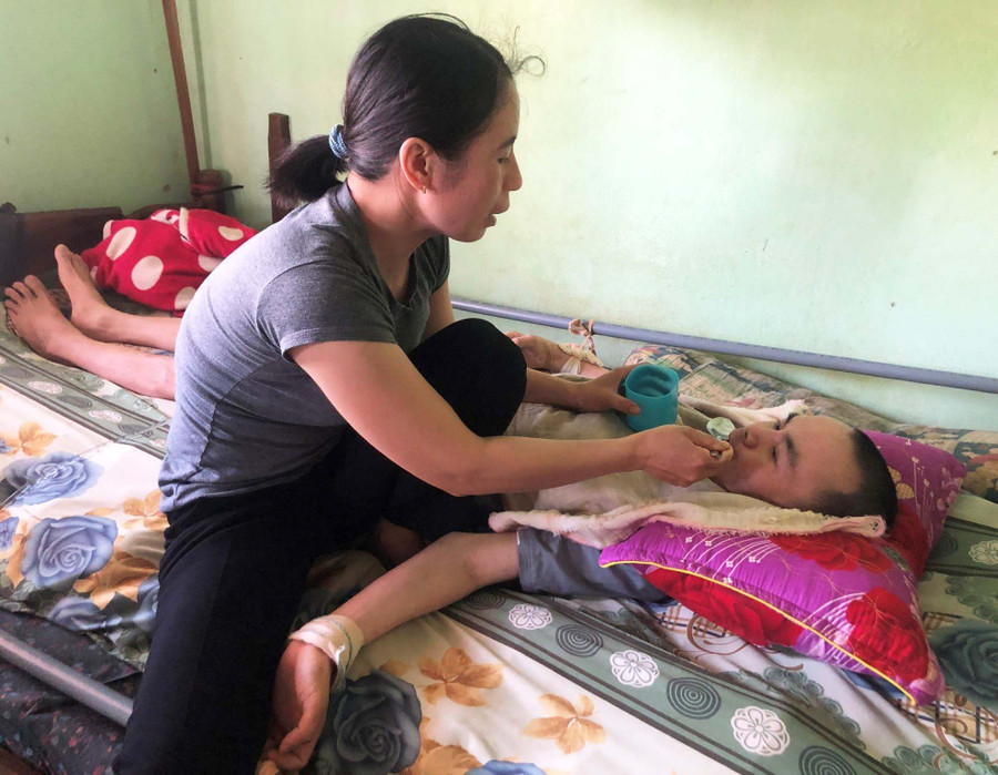 Chị Phạm Thị Tuyên chăm sóc chồng. Ảnh: Anh Huy