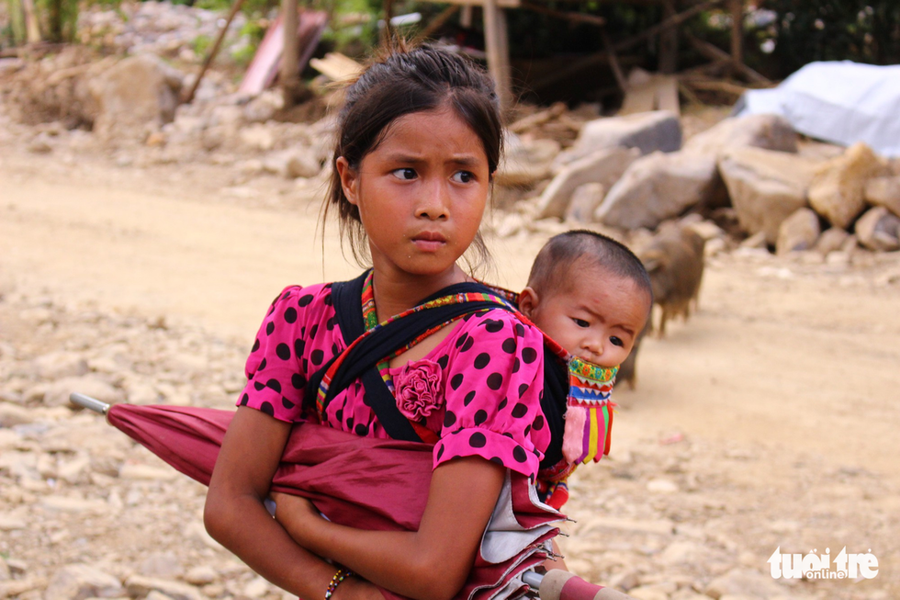  Cô bé Lò Thị Duyên (học sinh lớp 4, ở Mường La, tỉnh Sơn La) thay mẹ địu em trên lưng khi mẹ vắng nhà. Em được chị địu đi chơi nên không còn khóc nhè