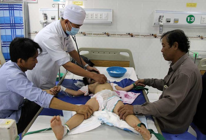 Bác sĩ thăm khám 1 trong 3 bé bị cha pha thuốc trừ sâu vào sữa cho uống.