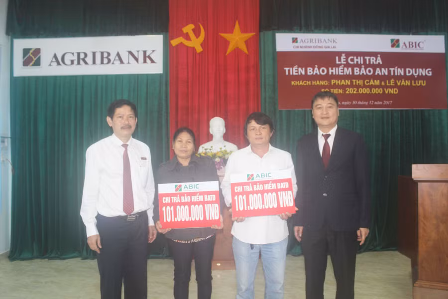 Lãnh đạo Agribank Đông Gia Lai và ABIC Đak Lak trao số tiền chi trả bảo hiểm BATD cho gia đình khách hàng. Ảnh: S.C