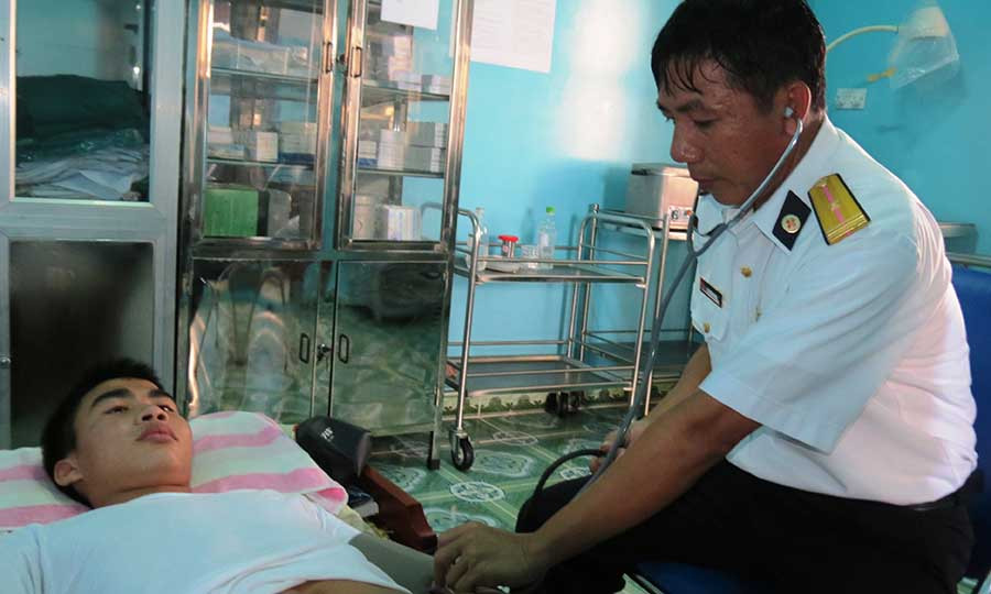Bác sĩ Bùi Đình Dong ở Nhà giàn DK1/2 khám bệnh cho ngư dân. Ảnh: Mai Thắng Bác sĩ Bùi Đình Dong ở nhà giàn DK1/2 khám bệnh cho ngư dân bị bí tiểu. Ảnh: Mai Thắng