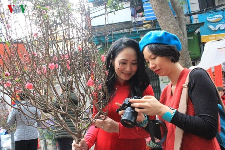 Người dân Hà Nội đổ xô ra chợ hoa để mua đào chơi tết và chụp ảnh cùng hoa sáng 14-2.