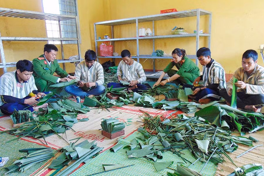 Cán bộ quản giáo Trại tạm giam T20 cùng phạm nhân gói bánh chưng đón Tết. Ảnh: Lê Anh