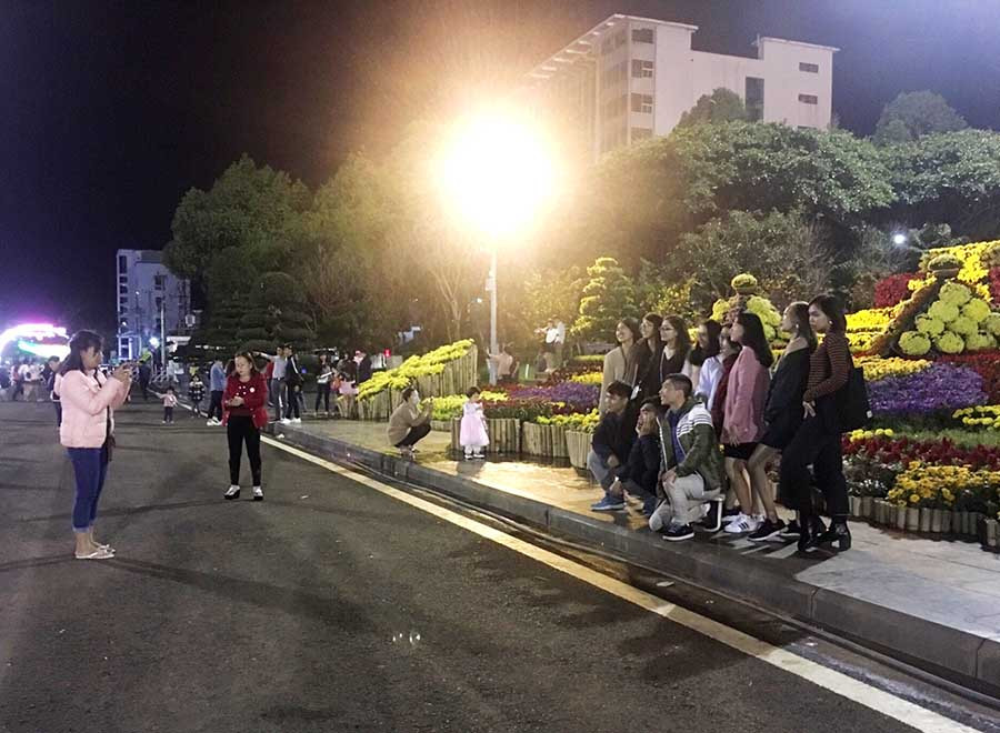 Nhiều bạn trẻ chụp ảnh check-in lưu lại những khoảnh khắc đẹp bên đường hoa Xuân. Ảnh: Hải Lê