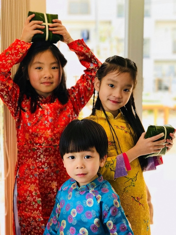 Con em người Việt tại Nhật mặc áo dài, bên những chiếc bánh chưng mới gói. 