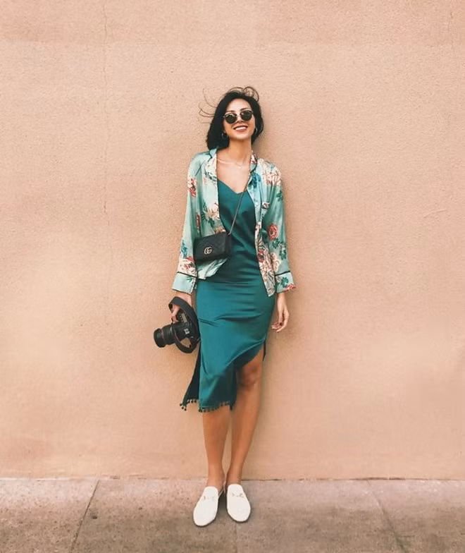 Đầm xanh lá cũng là lựa chọn của Minh Triệu trong tuần qua. Tuy nhiên, siêu mẫu ưu tiên cho thiết kế đầm 2 dây, trưng dụng sơ mi hoa kiiểu pyjama làm áo khoác bên ngoài và mang giày xỏ hết mực phóng khoáng.