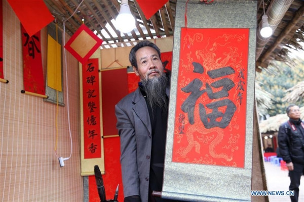  Một ông đồ viết chữ “Phúc”, có nghĩa là may mắn, trên giấy đỏ.