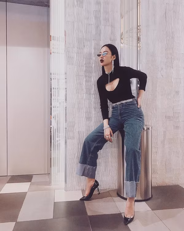 Angela Phương Trinh thể hiện sự sành điệu khi chọn các kiểu phụ kiện mắt kính, vòng cổ, hoa tai hot trend 2018 để tạo điểm nhấn cho set đồ gồm áo thun ôm, quần jean ống rộng.