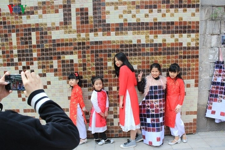 Những em bé thích thú chụp ảnh bên những bức tranh bích họa trên phố Phùng Hưng.