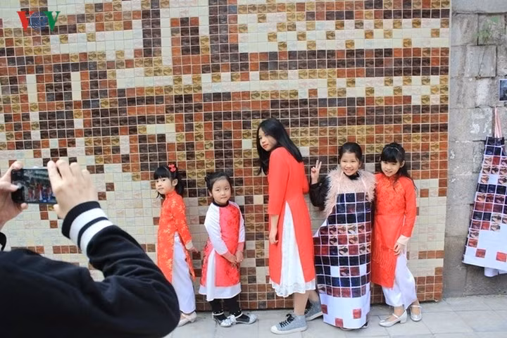 Những em bé thích thú chụp ảnh bên những bức tranh bích họa trên phố Phùng Hưng.