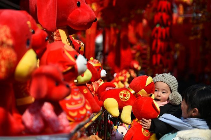  Một em bé vui thích ôm chú chó bông màu đỏ tại Hợp Phì, tỉnh An Huy, Trung Quốc.