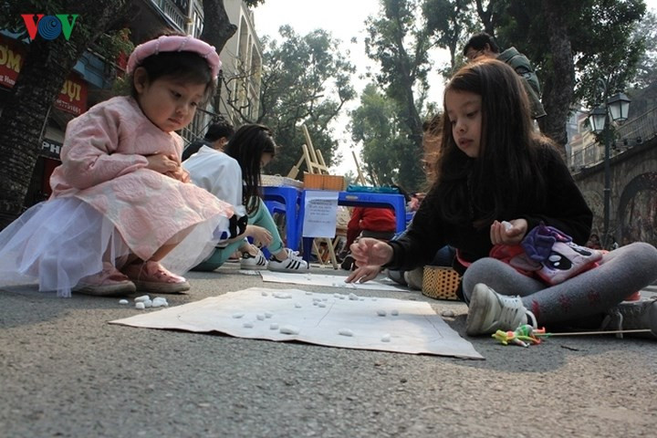 Nhiều em nhỏ xúng xính cùng những bộ áo dài đủ màu sắc đi cùng bố mẹ ra các điểm vui chơi để thưởng thức không khí xuân đang về tại Thủ đô.