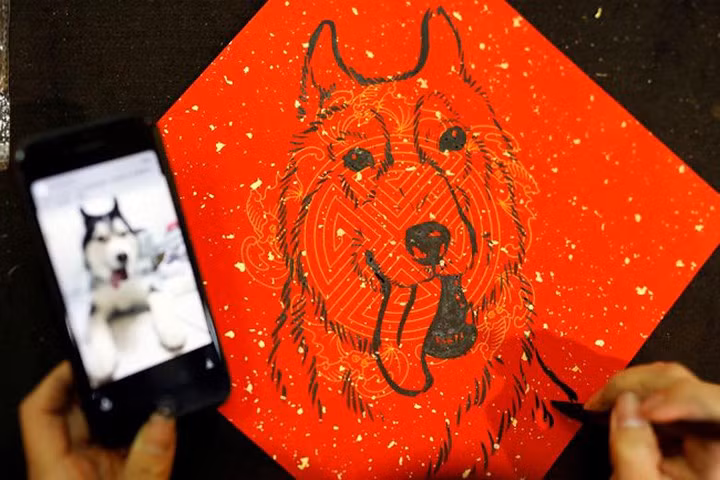  Một họa sỹ đang vẽ tranh con chó – biểu tượng năm mới Mậu Tuất 2018 tại một khu chợ ở Đài Loan, ngày 12/2.