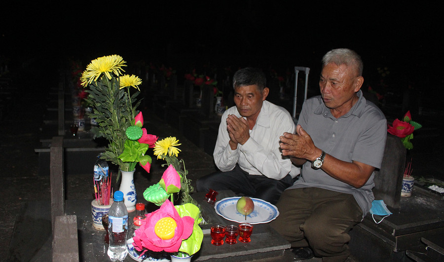 Ông Lê Phú Khắc (bìa trái) và ông Lê Phú Minh thắp hương lên phần mộ liệt sĩ Lê Phú Trần. Ảnh: Phan Lài 