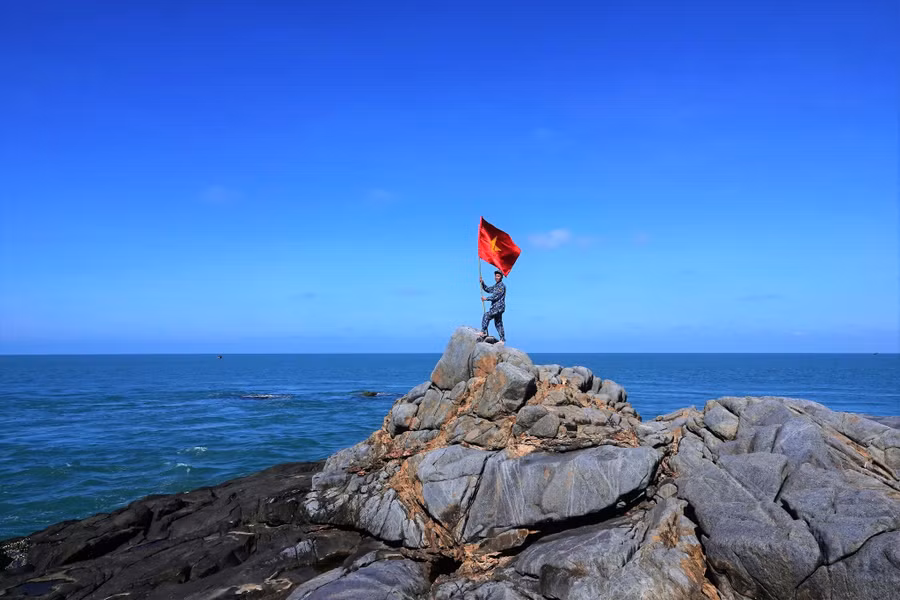 Cắm cờ Tổ quốc lên điểm cao nhất của Hòn Đá Lẻ. Ảnh: Ngô Trần Hải An