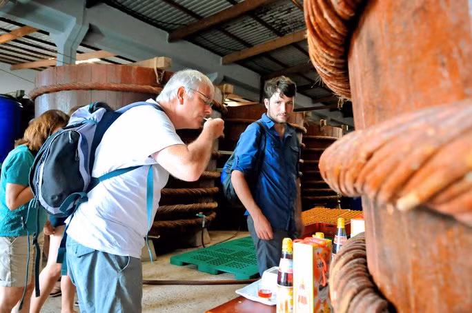 Du khách nước ngoài thích thú khi nếm thử nước mắm Phú Quốc được lấy từ thùng gỗ