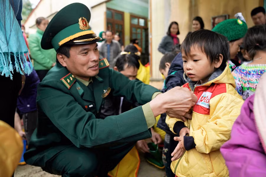 Thượng tá Bùi Văn Huân (Phó trưởng phòng Phòng chống ma túy và tội phạm, BĐBP Hà Giang) cùng cán bộ chiến sĩ Đồn BP Nghĩa Thuận tặng áo ấm cho trẻ em biên giới Quản Bạ. Ảnh: Mai Thanh Hải