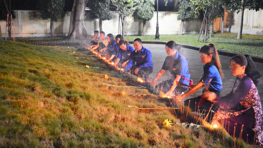 Đoàn viên thanh niên thắp nến tri ân tại ngôi mộ chung. Ảnh: Lam Nguyên