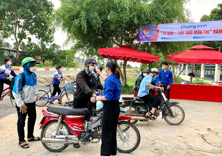 Các tình nguyện viên đo thân nhiệt. sát khuẩn tay cho các thí sinh tại điểm thi Trường THPT Lý Thường Kiệt. Ảnh: Vũ Chi